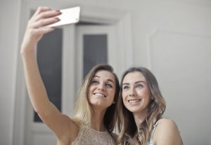 two women taking pictures and talking to maintain a long-distance friendship after you move