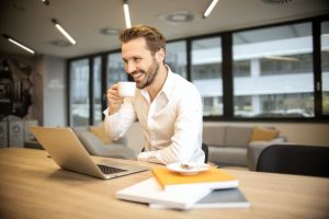 Man on his laptop in an office drinking coffee