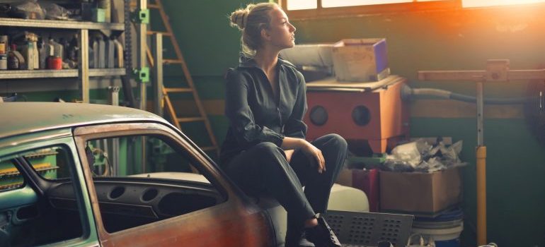 A woman sitting on a car in a garage