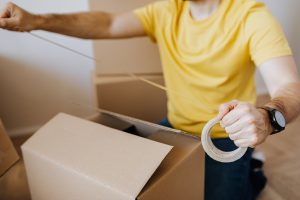 person taping a cardboard box