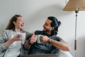 two people laughing and drinking coffee, wondering should you rate your movers after the relocation?