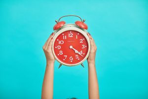 Person holding an analog clock.