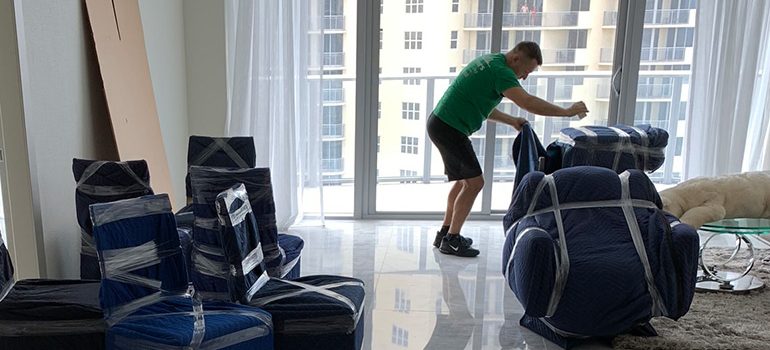 A mover surrounded by wrapped furniture preparing items for storage in Boca Raton.