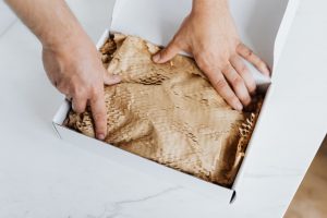 hands packing a box with packing paper