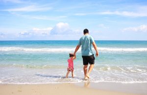 a father walking with his daughter on the beach