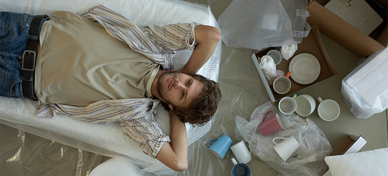 man relaxing among unpacked boxes