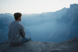 A man sitting and thinking on a cliff