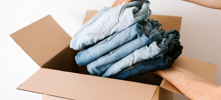 crop-man-packing-casual-clothes-into-carton-box