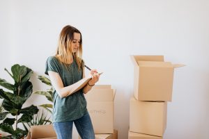 boxes and a woman writing a plan on how to reduce waste during your long-distance move