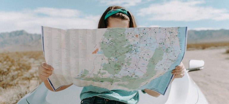 Woman in front of a car reading a map