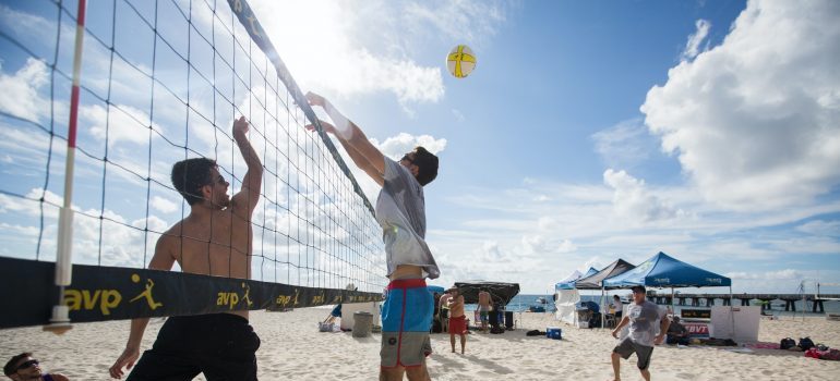 Cheerful people playing volleyball on a sunny beach.