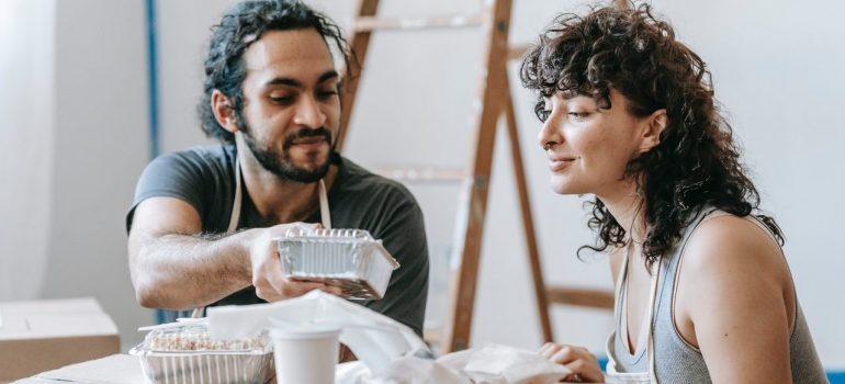 a man and woman are sitting and eating delivery food