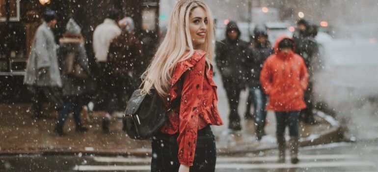 A woman on a street after moving to New York from Florida while it snows 