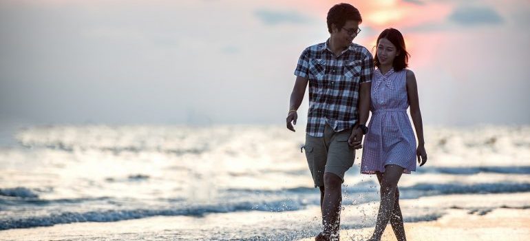 A couple walking along a white sandy beach representing a beach where you can have a rental property in Sunny Isles Beach.