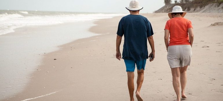 Man and woman walking barefoot on the beach thinking about the cost of living in Florida vs California