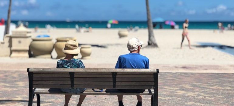 A man a a woman sitting on a beach looking onto the beach representing buying a rental property in Boca Raton