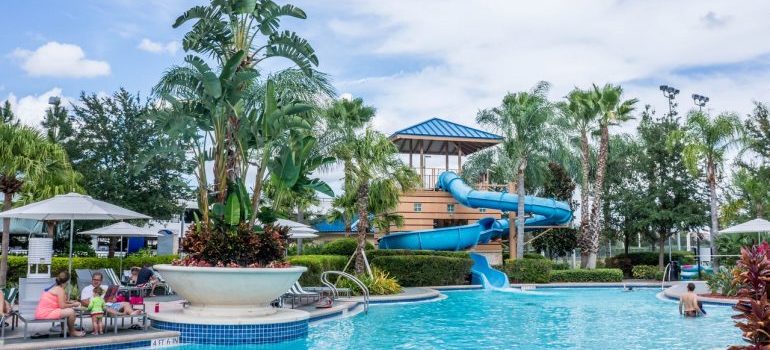 a view onto a waterpark (pool, palm trees and a slide)