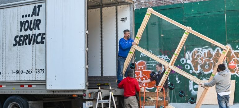 Movers loading a truck with an oversized fragile item