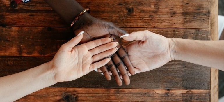 Three hands stacked on top of one another on top of a wooden table