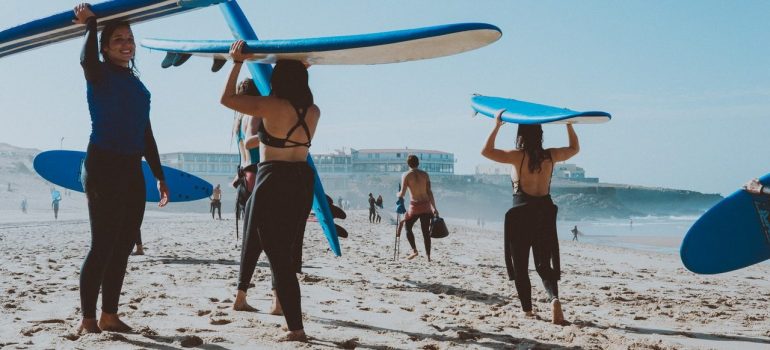 A group of surfers carrying surfboards and going towards the Ocean. 