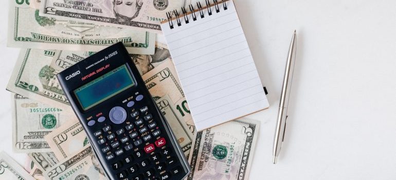 Money, calculator, pen, and a notepad on the table