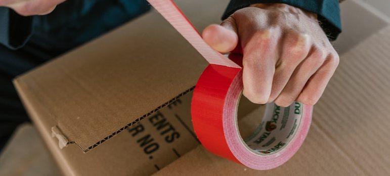 a man holding a duct tape above a box