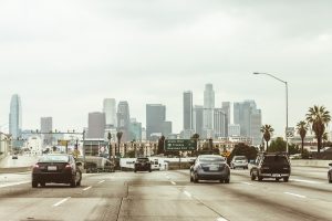 Cars on the road and Los Angeles building in front of them.