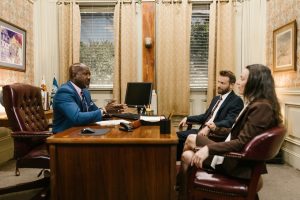 The judge, husband and wife sit around a desk in the law office and talk about interstate moving after divorce.