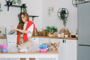 A woman is sorting things in the kitchen to decide what to leave behind when moving from Miami to Los Angeles.