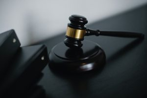 A small judge gavel placed on table near folder.