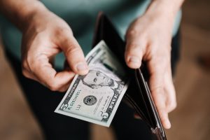 A person taking out a one dollar bill out of their pocket