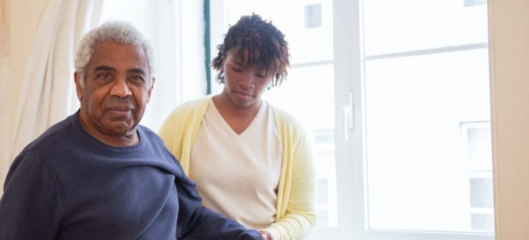 a nurse helping an elderly man walk