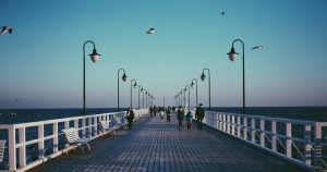 People are walking on the Pompano Beach Pier that stretches into the Atlantic Ocean.