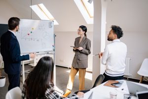 People standing in front of the whiteboard and discussing how to delegate jobs of packing for a corporate move.