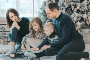 The family is sitting together under the Christmas tree and watching a book in a Hallandale Beach or Boynton Beach home.