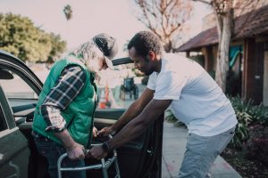 A man helping an elderly woman get out of the car