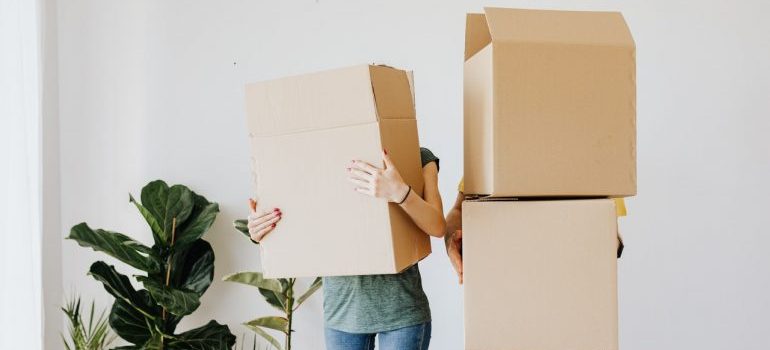 Two persons holding empty carboard boxes.