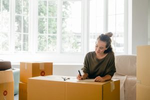 A woman writing a plan on a moving box