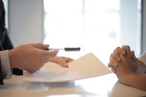 A person sgiivng other person documents to sign