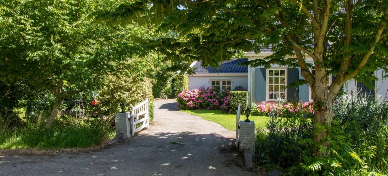 a picture of a home with flowers and hedges around it, taken from a driveway