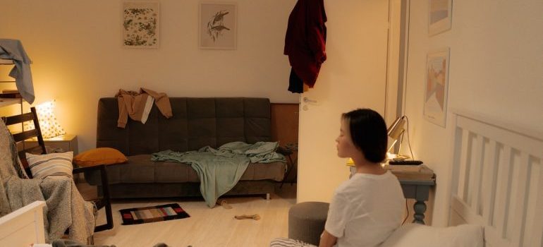 Girl sitting in a messy room.