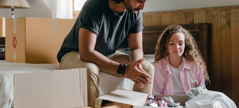 a couple sitting in the bedroom discussing which items to take with them