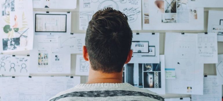 A man is looking at the papers on the wall