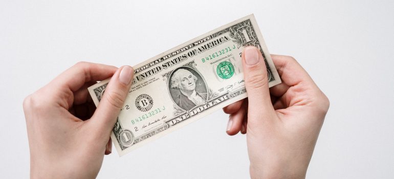 A person is holding a US dollar and can lower the costs by moving to a warmer climate