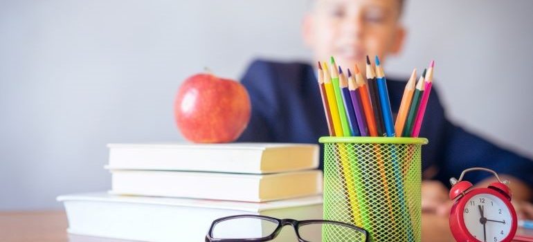 kid looking at apple and books