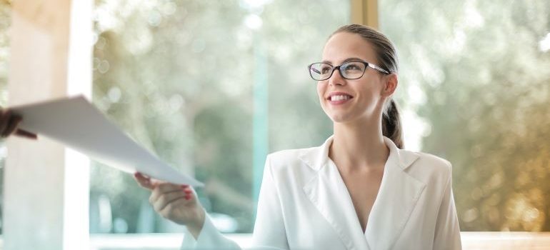 a woman smiling and holding papers