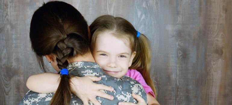 Woman in uniform hugging a little girl.