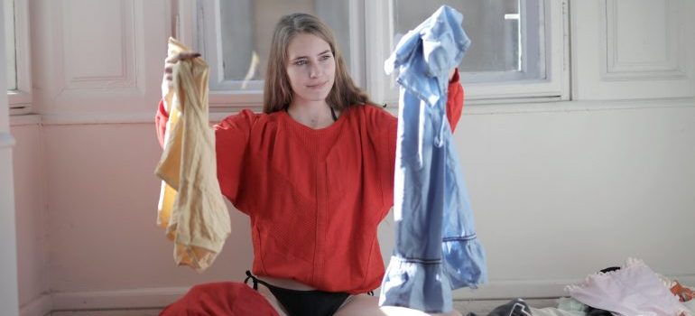 woman in red shirt holding clothes