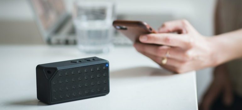 Person holding phone beside black portable speaker