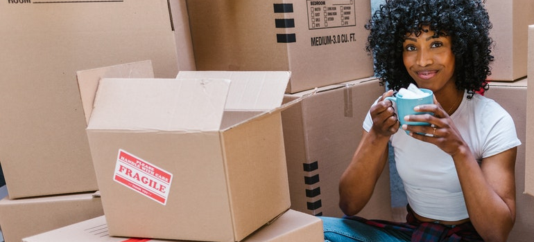 a girl drinking coffee and sitting next to a box